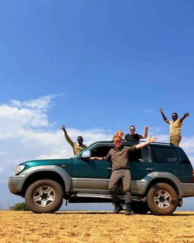 Arms up on the savannah after a morning of good sightings — Volcano Peaks Safaris Rwanda guests